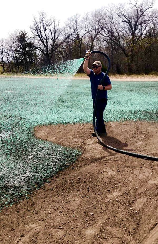 A man is spraying grass on a field with a hose