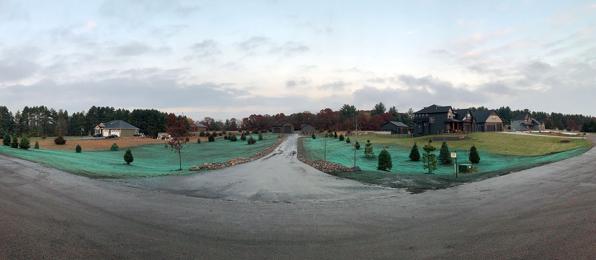 A panoramic view of a residential area with a lot of trees on the side of the road