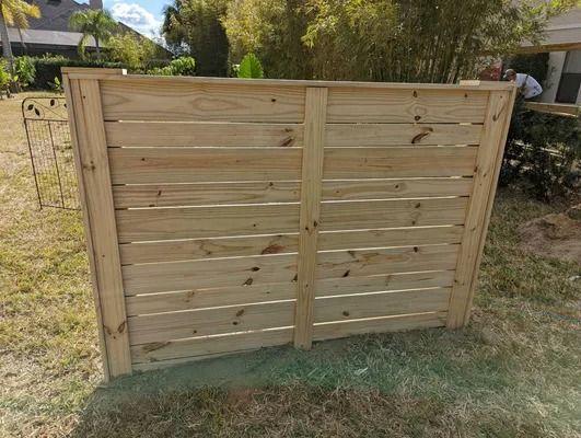 Wooden horizontal slat fence in a grassy yard.