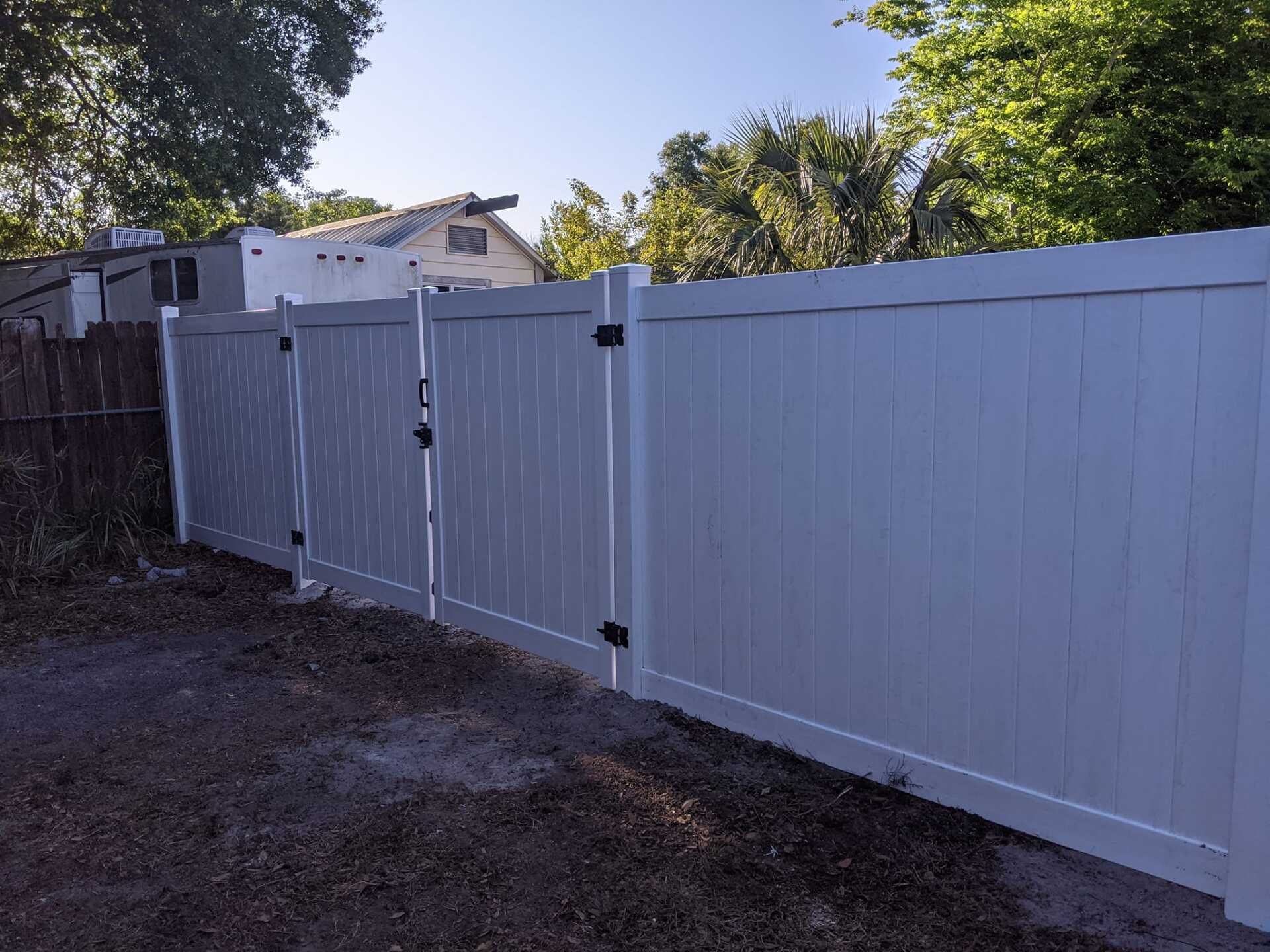 White vinyl fence with gate in front of a house. Black hinges and latch.