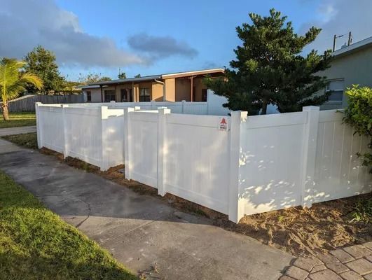 White vinyl fence in front of a house on a sunny day.