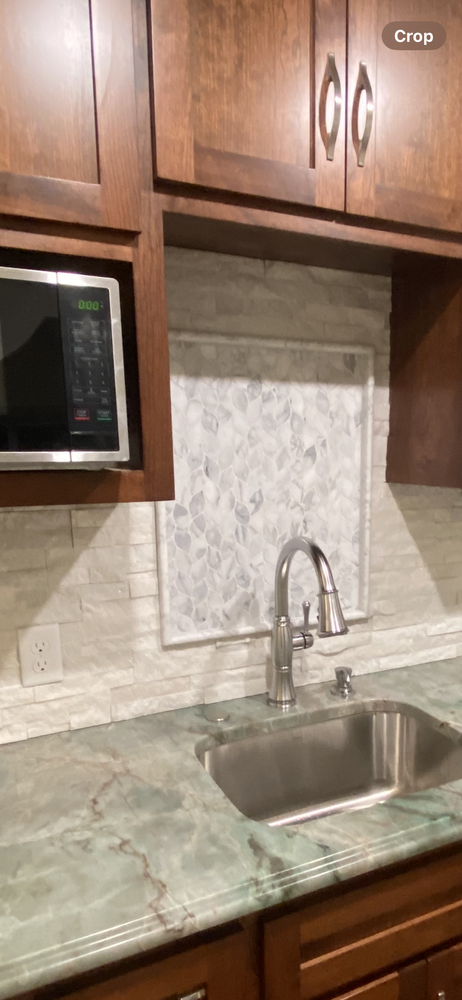 Kitchen with microwave, sink, and green countertop, with brown cabinets.