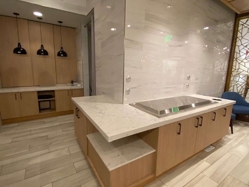 Modern kitchen with light wood cabinets, quartz countertops, and stainless steel cooktop.
