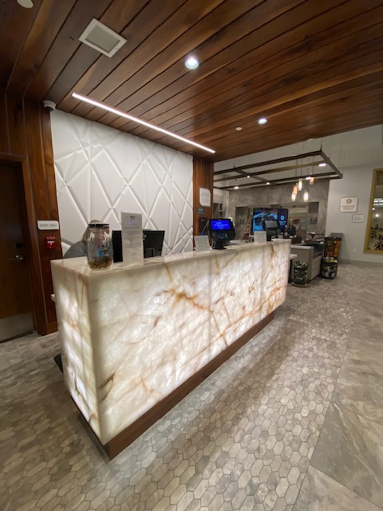 Lit reception desk with marble surface, wooden accents, and tiled floor.