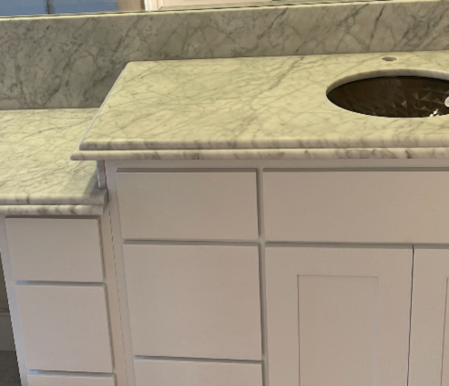 White bathroom vanity with marble countertop and a round sink.
