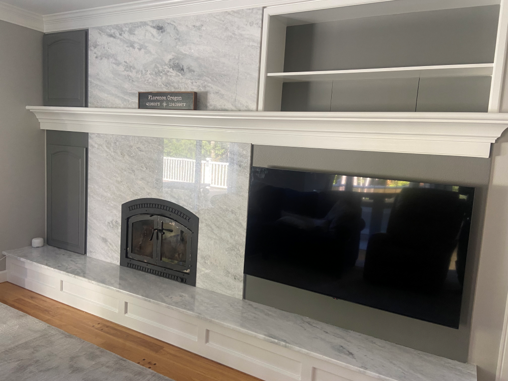 Fireplace with marble surround, built-in shelves, and mounted TV. White trim, gray accent.