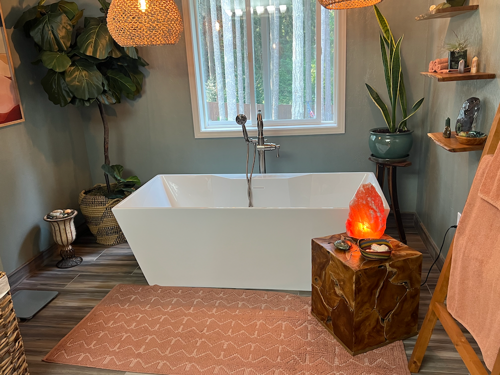 Cozy bathroom with a white tub, rug, plants, and a Himalayan salt lamp.