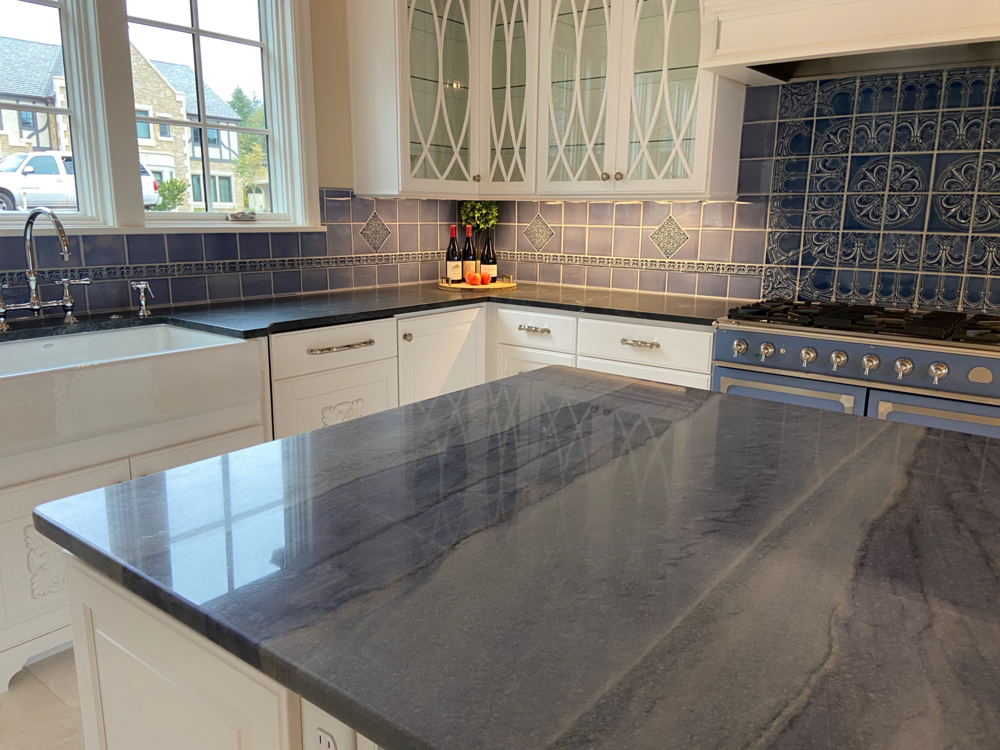 Kitchen with white cabinets, blue tile backsplash, and blue countertop island.
