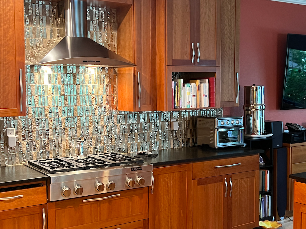 Kitchen with stainless steel appliances, dark cabinets, and backsplash.