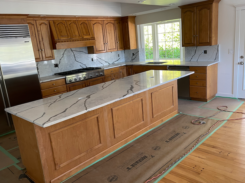 Kitchen with light wood cabinets, quartz countertops, and a large island.