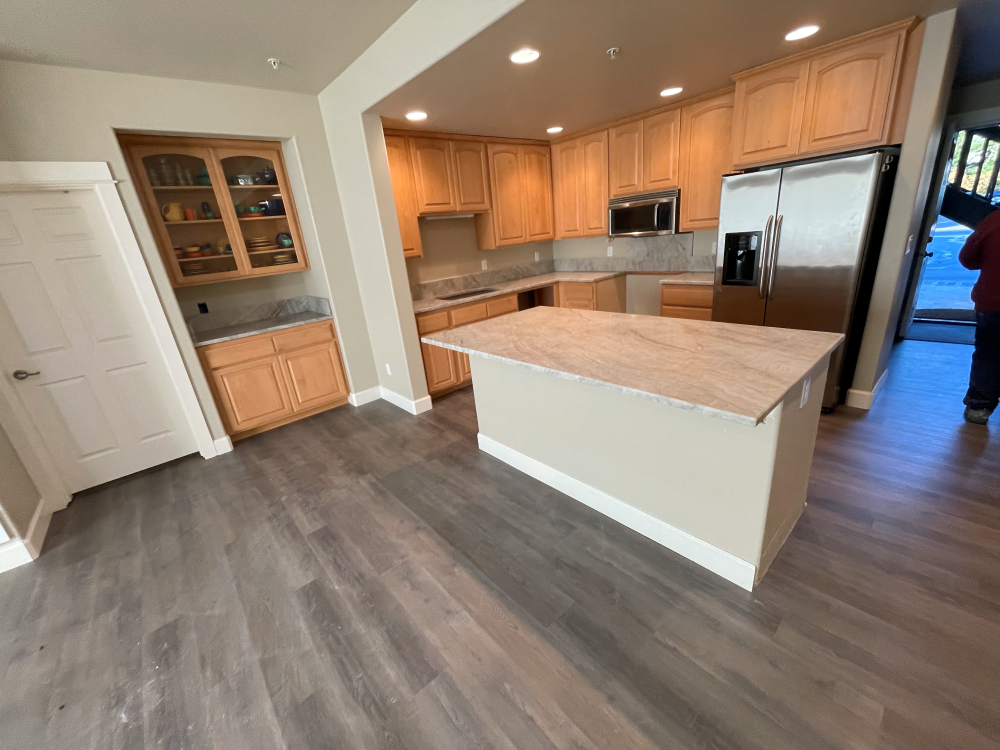 Kitchen with wooden cabinets, stainless steel refrigerator, and island with a light-colored countertop.