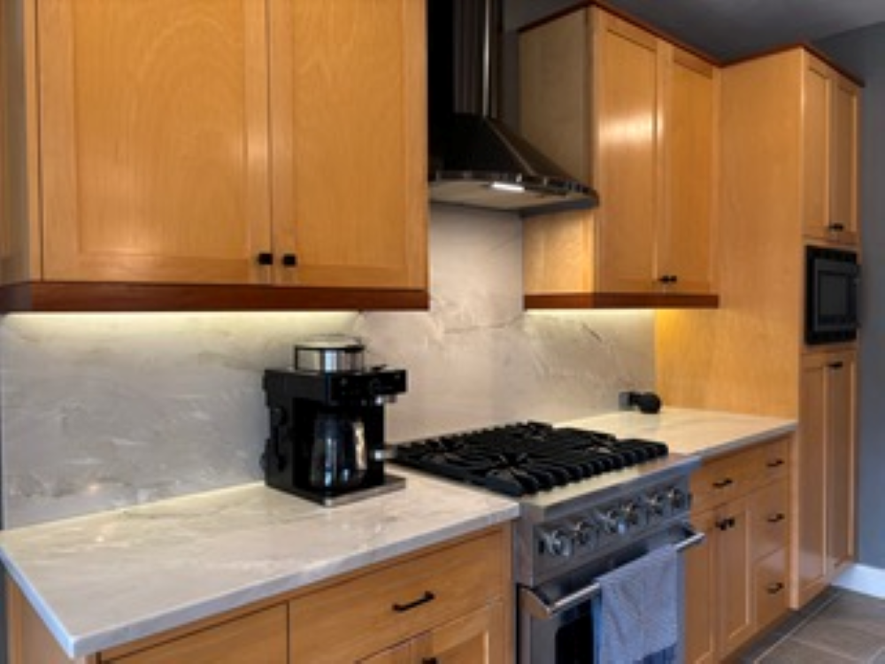 Kitchen with light wood cabinets, white countertops, and stainless steel appliances.