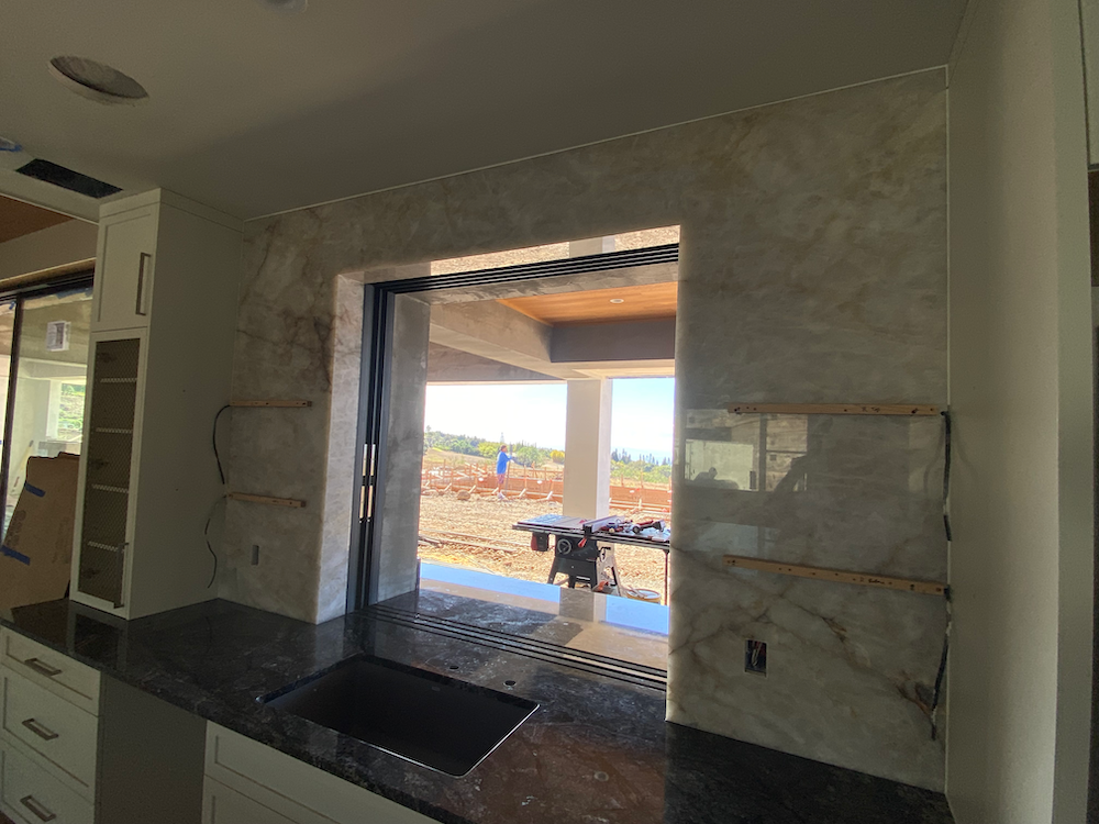 Kitchen with marble tile backsplash, window, granite countertop, and outdoor view.