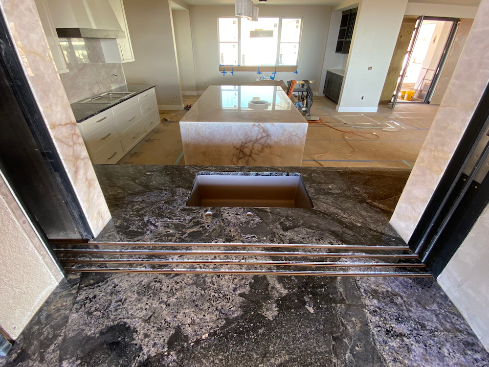 Kitchen under construction with granite countertops and island, neutral tones.