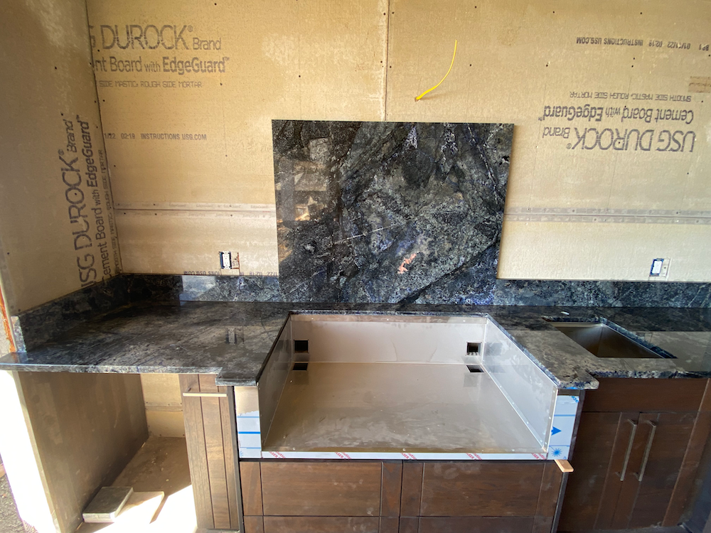 Granite countertop with backsplash installed on cabinets, construction site interior.