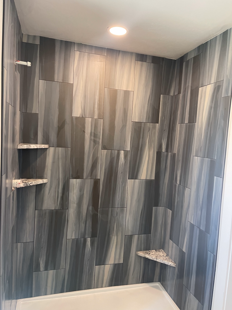 Gray and blue patterned tile shower with built-in stone shelves.