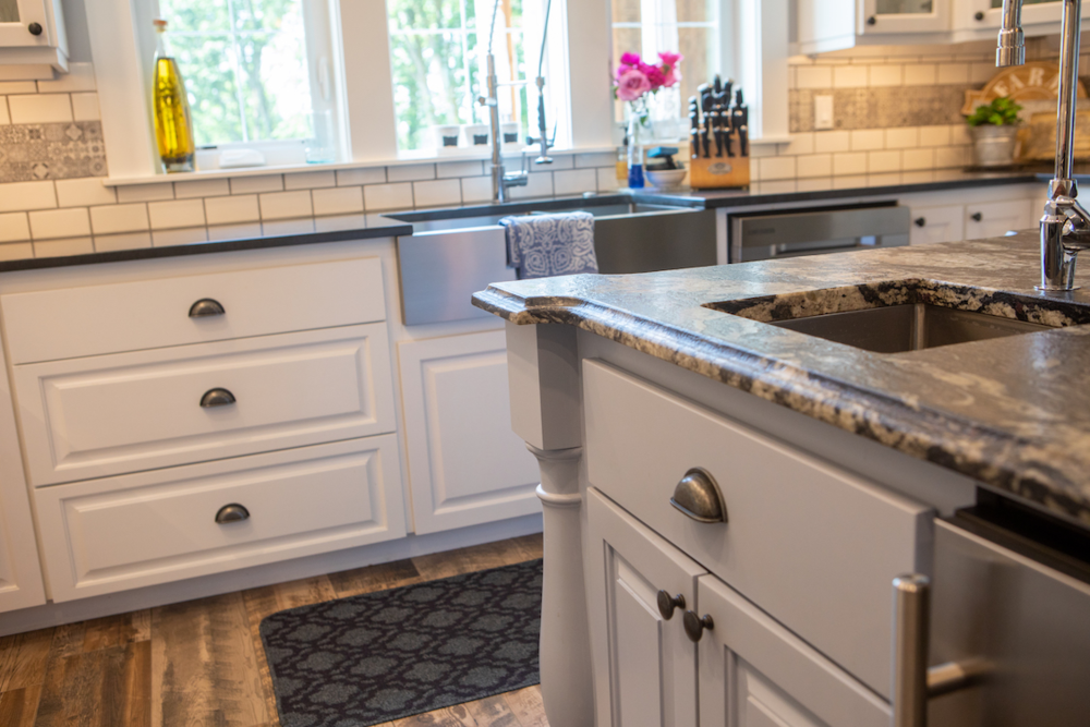 White kitchen cabinets with black countertops and stainless steel sink.