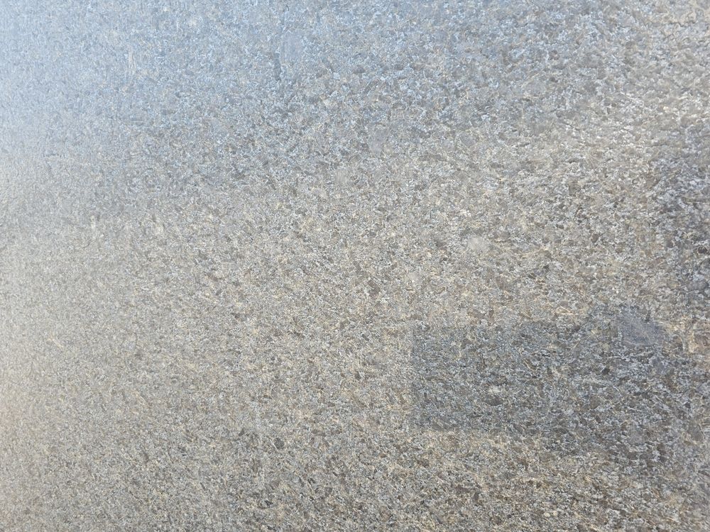 Close-up of a gray, speckled concrete surface with a dark patch in the lower right.