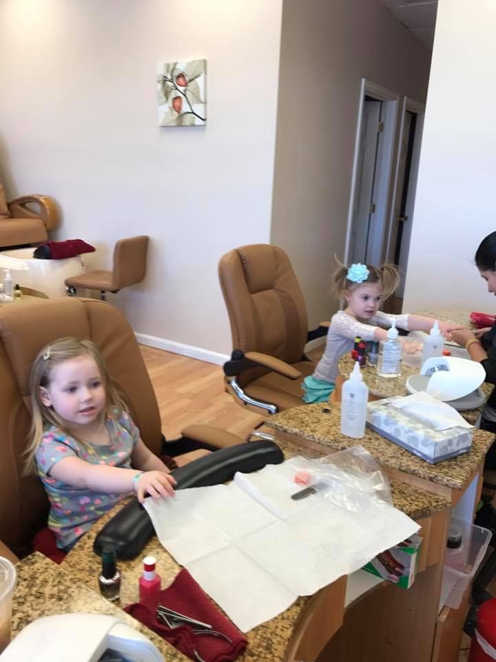 Two little girls are getting their nails done at a nail salon.