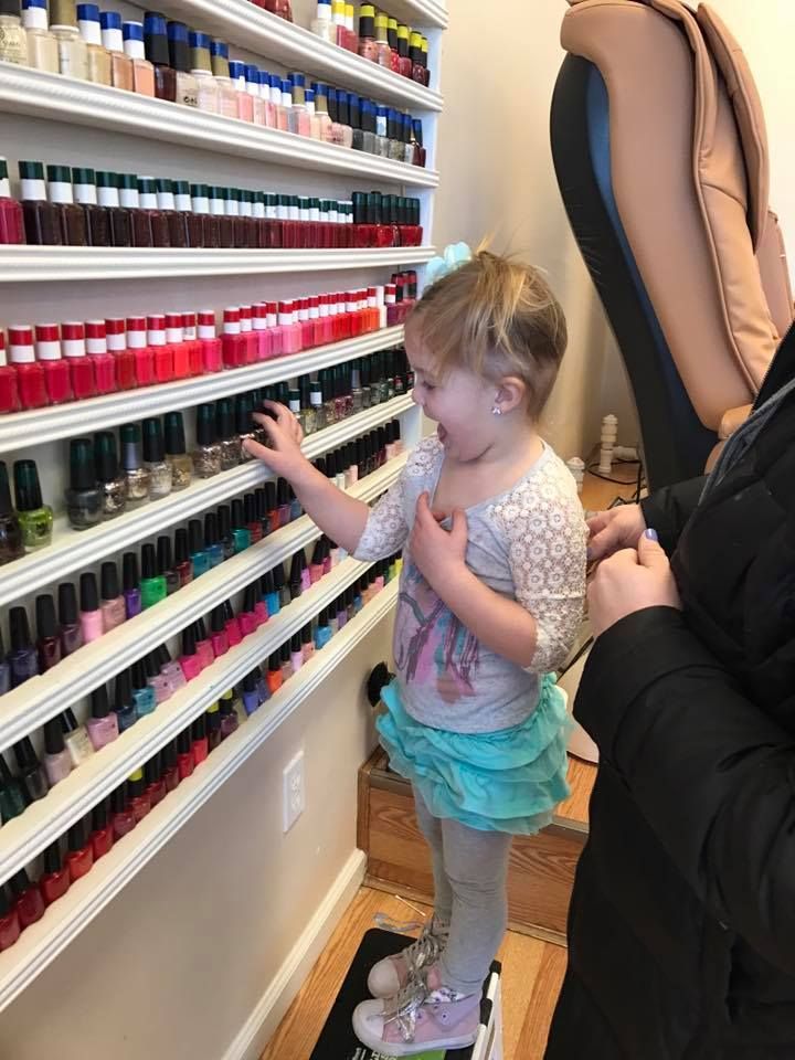 A little girl is looking at a shelf of nail polish.