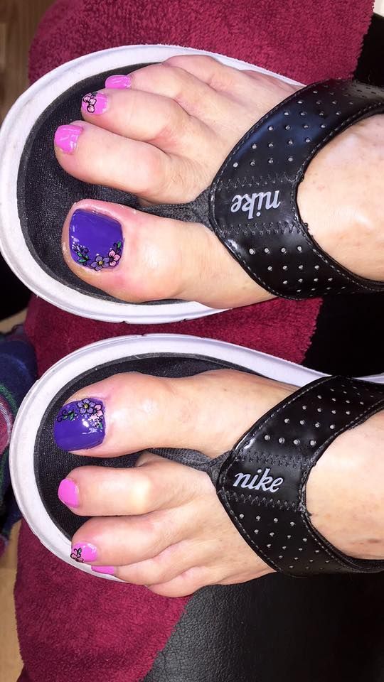 A close up of a person 's feet wearing flip flops with purple nails.