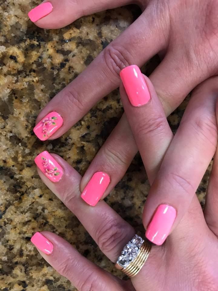 A woman 's hands with pink nails and a gold ring