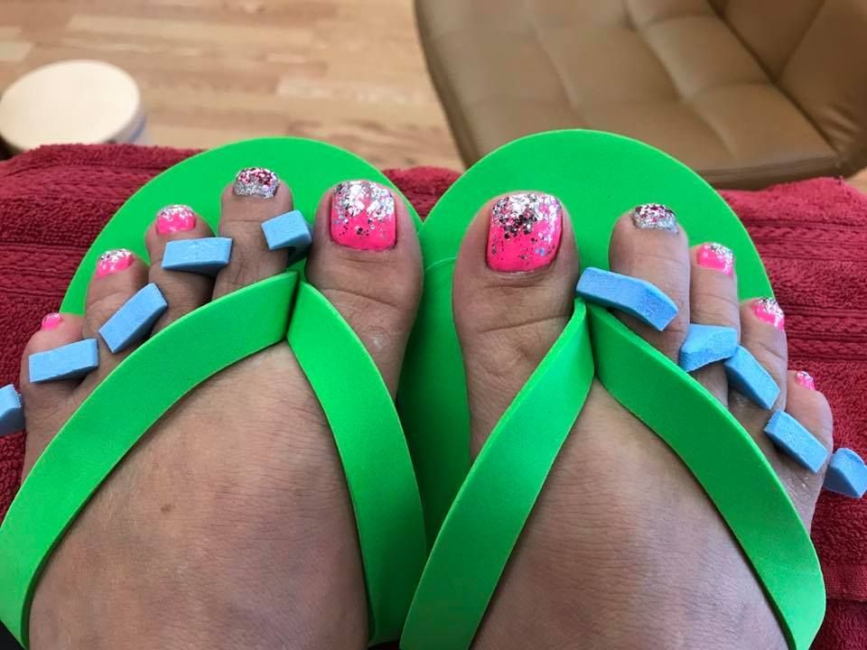 A woman 's feet with pink nails and green flip flops