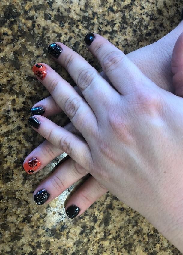 A close up of a person 's hand with black and orange nails