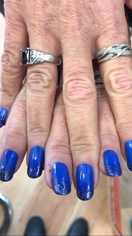 A close up of a person 's hands with blue nails and rings.