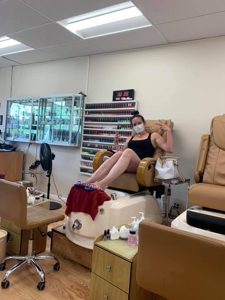 A woman is sitting in a chair in a nail salon.