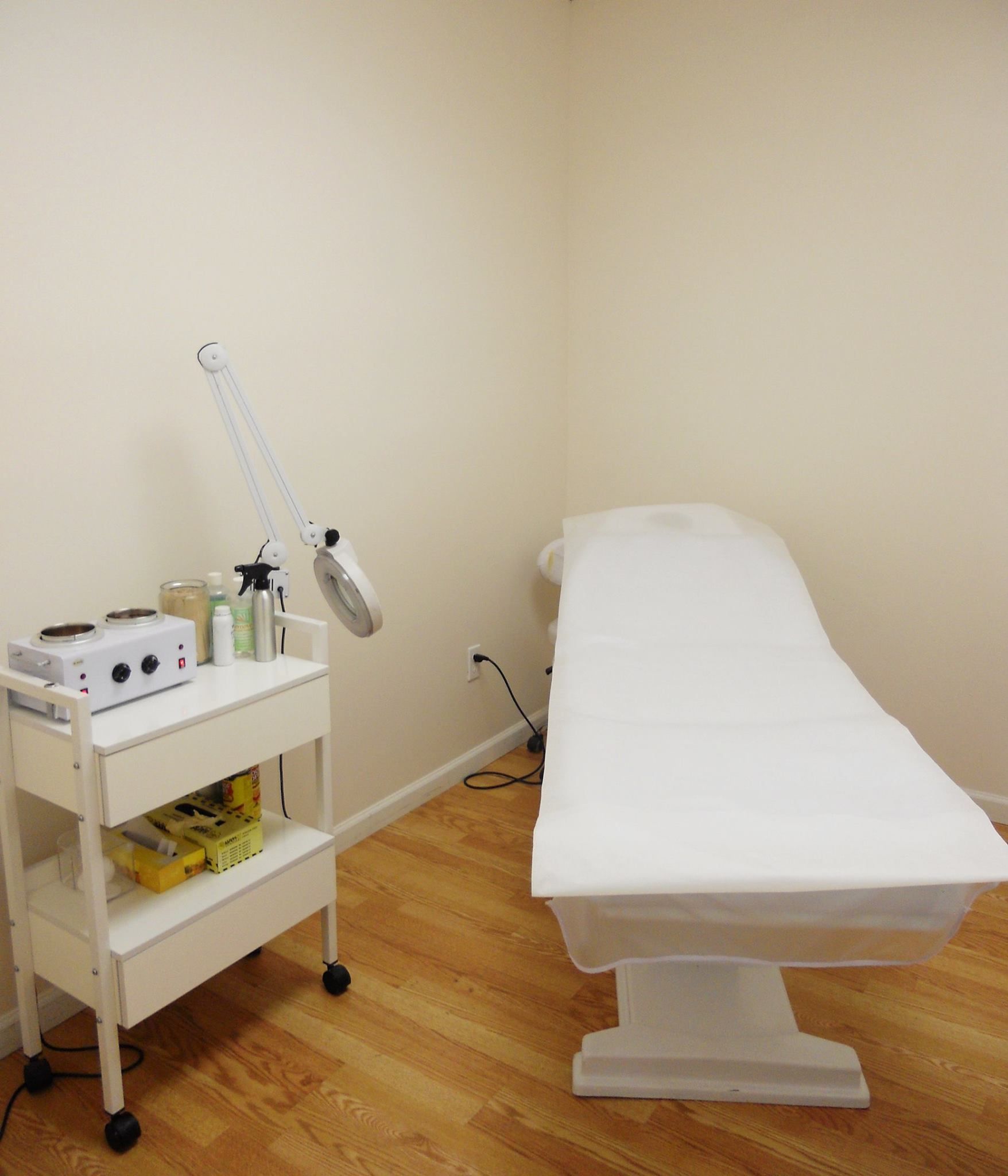 A room with a bed and a lamp on a cart