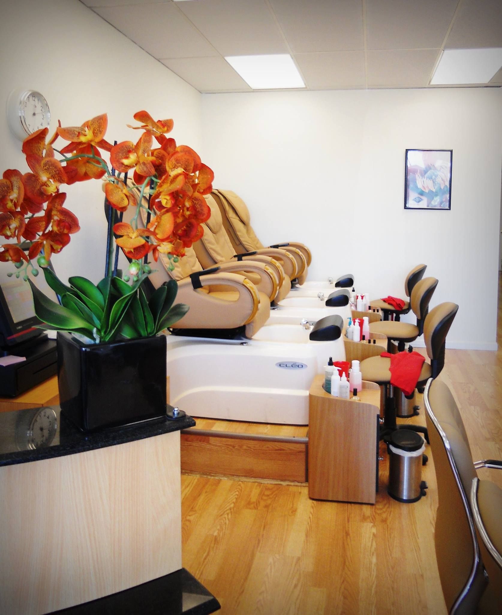 A row of chairs in a nail salon with a vase of flowers on the counter