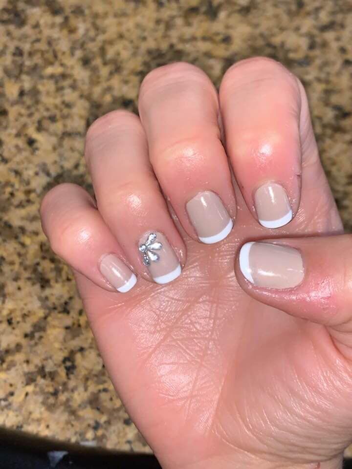 A close up of a person 's nails with a french manicure and a rhinestone.