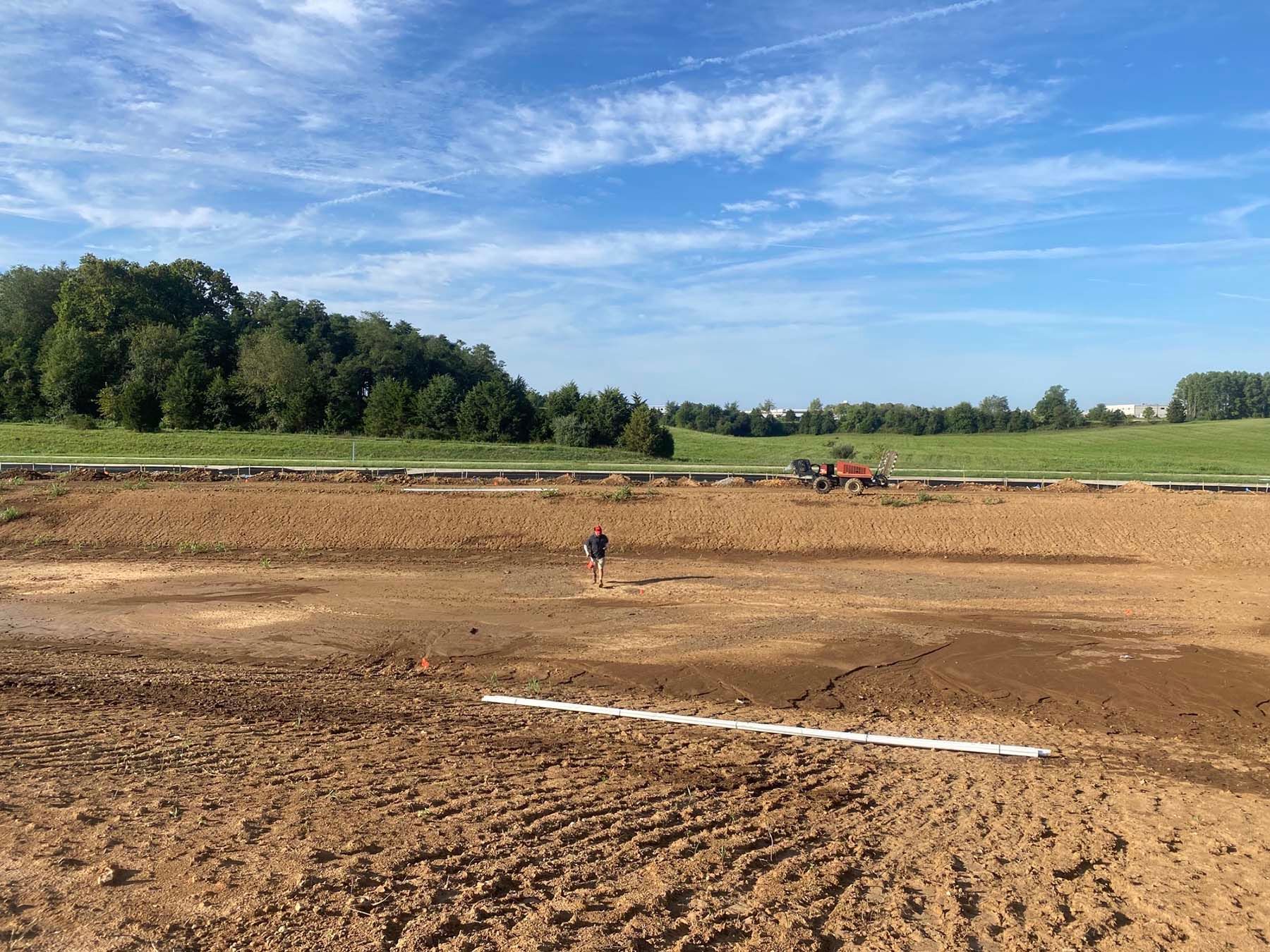 A muddy field with trees in the background on a sunny day.