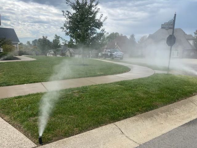 A lawn sprinkler is spraying water on a lush green lawn.