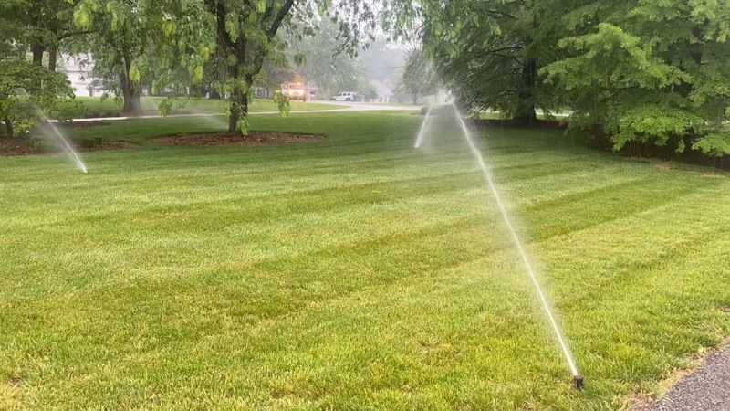 A lawn with sprinklers spraying water on it.