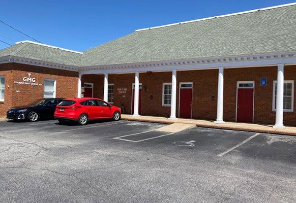 A red car is parked in front of a brick building