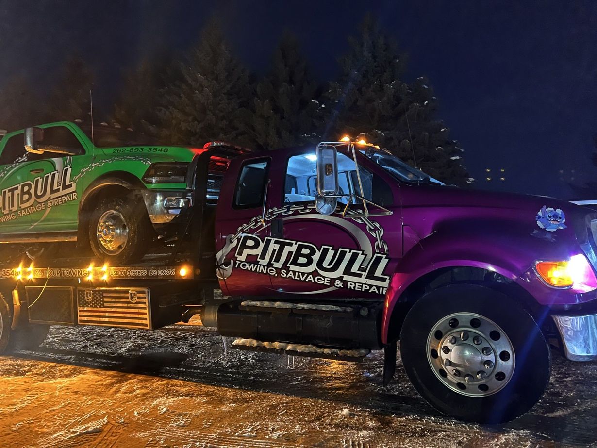 Two tow trucks, one green and one purple, branded