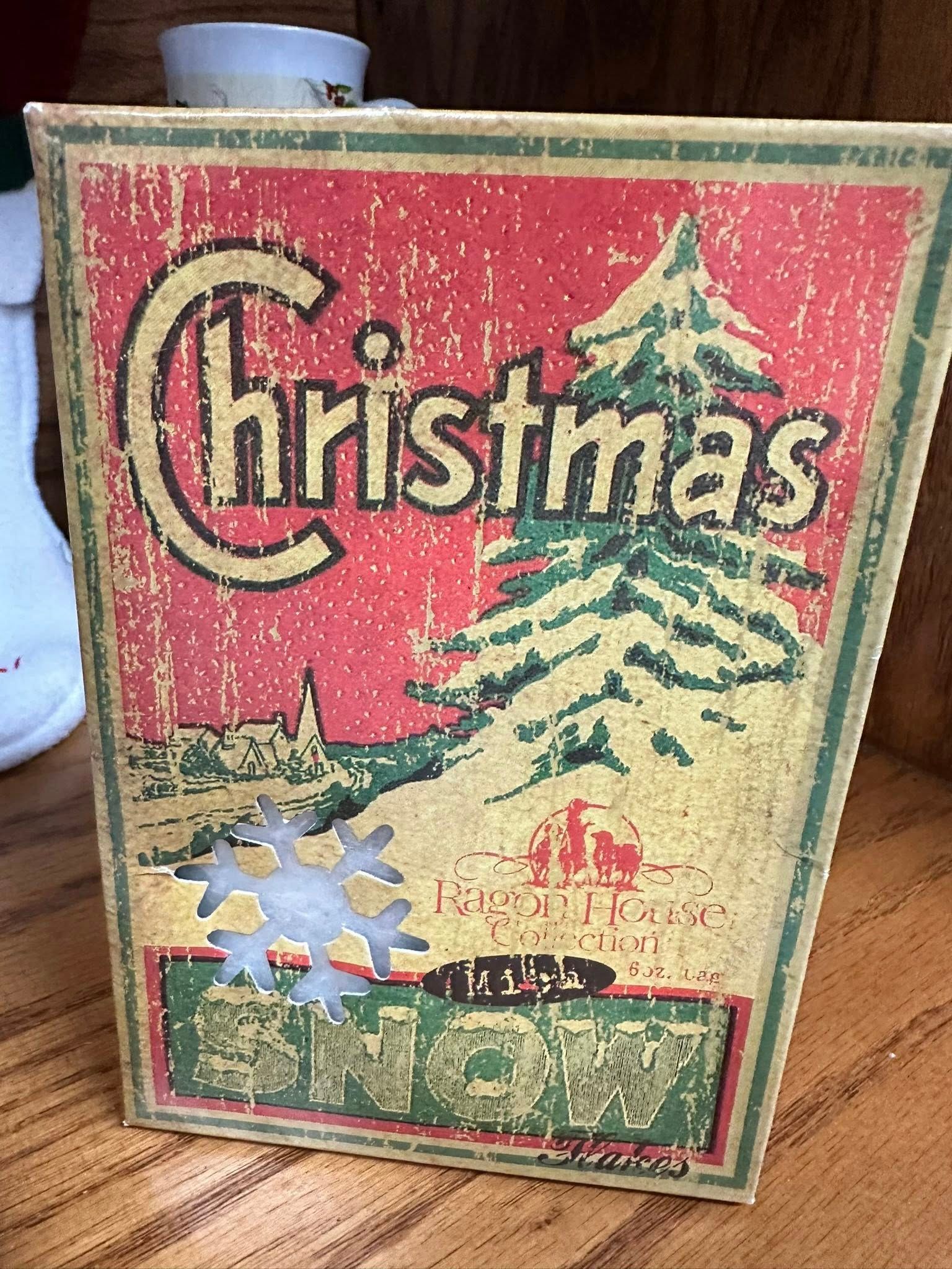 Christmas-themed vintage box with red background, a green Christmas tree, and a snowflake.