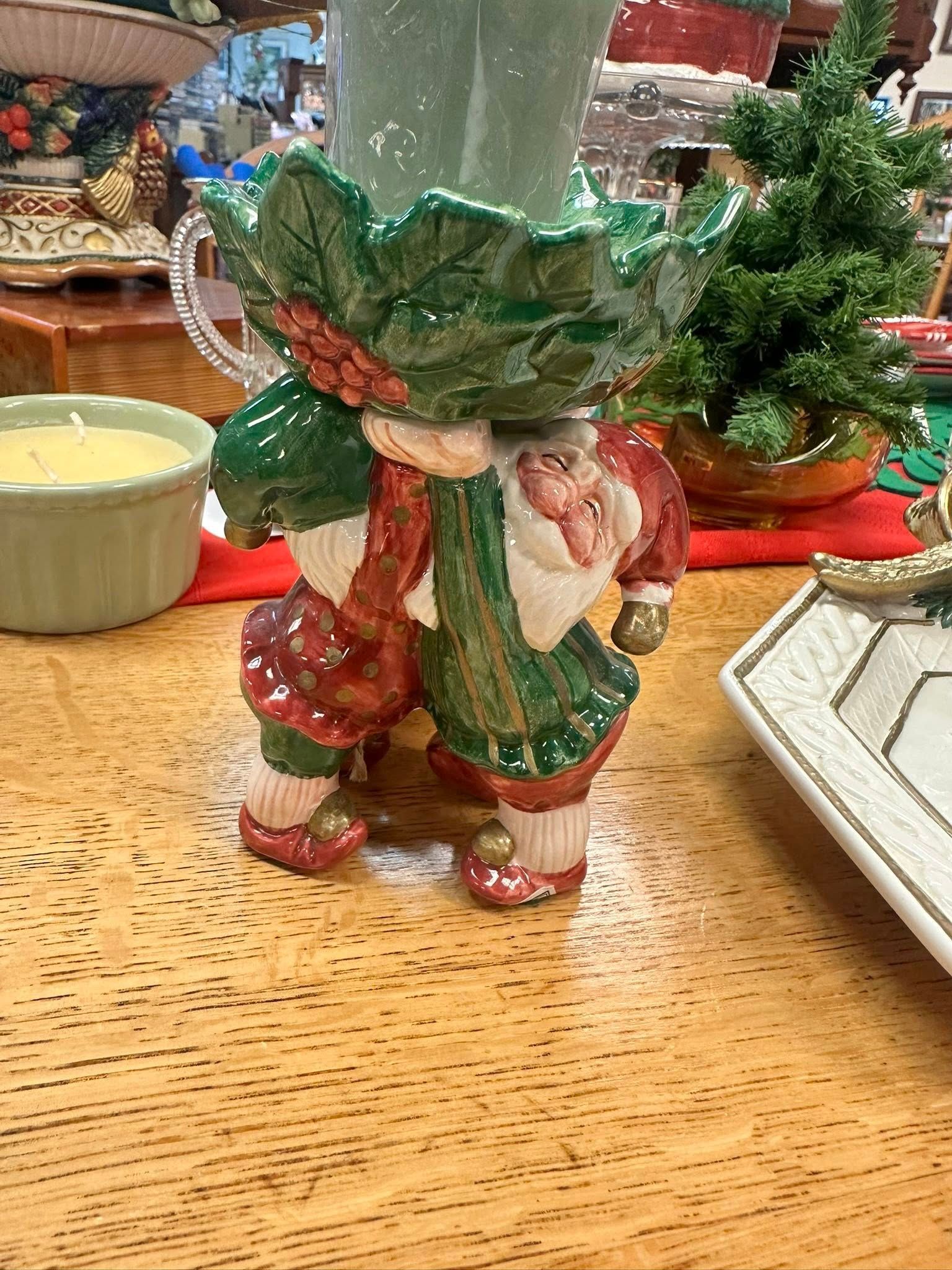 Ceramic Santa-shaped vase on a wooden table, green and red colors, festive.