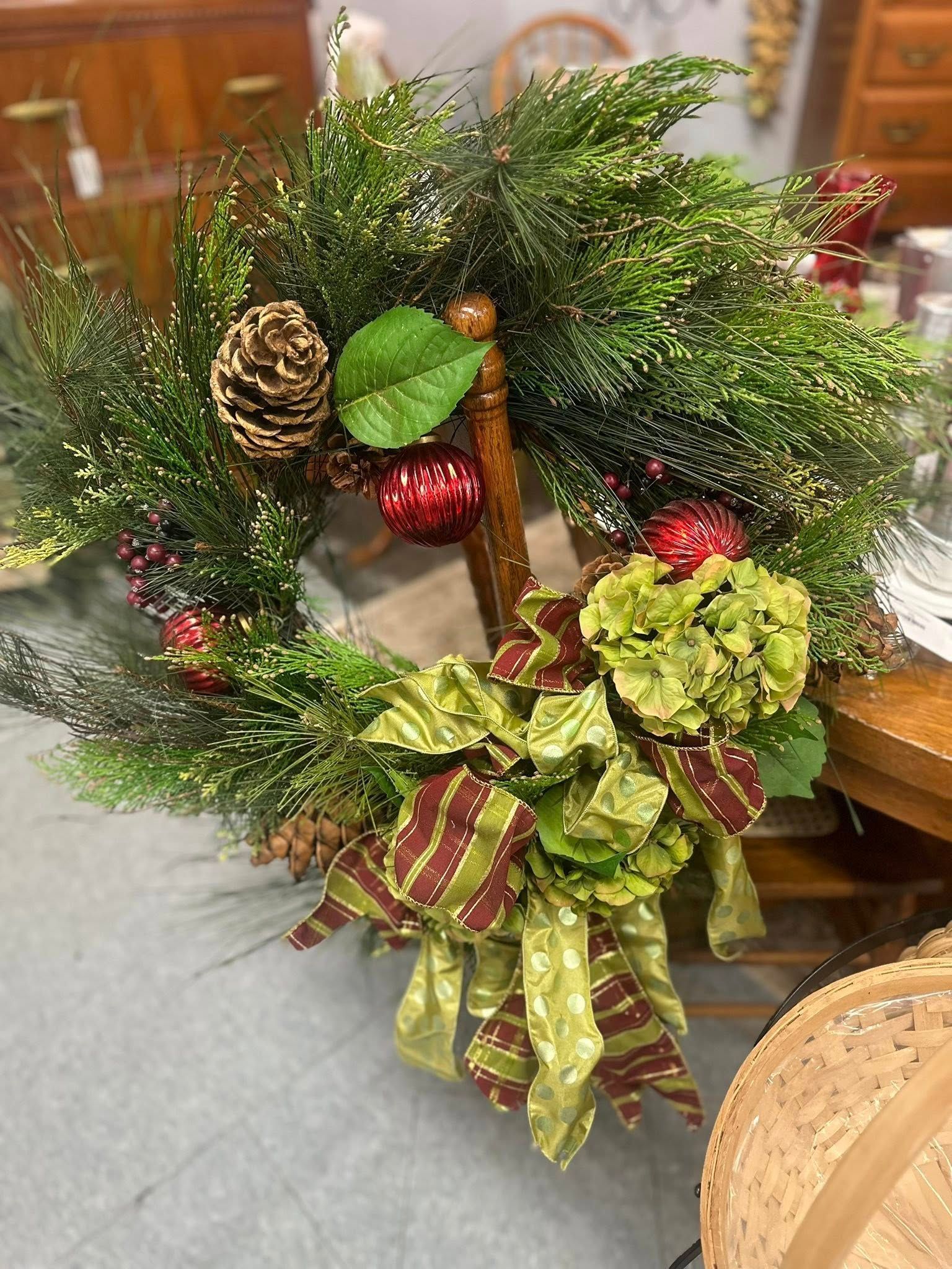Christmas wreath with pine, pinecones, ornaments, and green and burgundy ribbon.