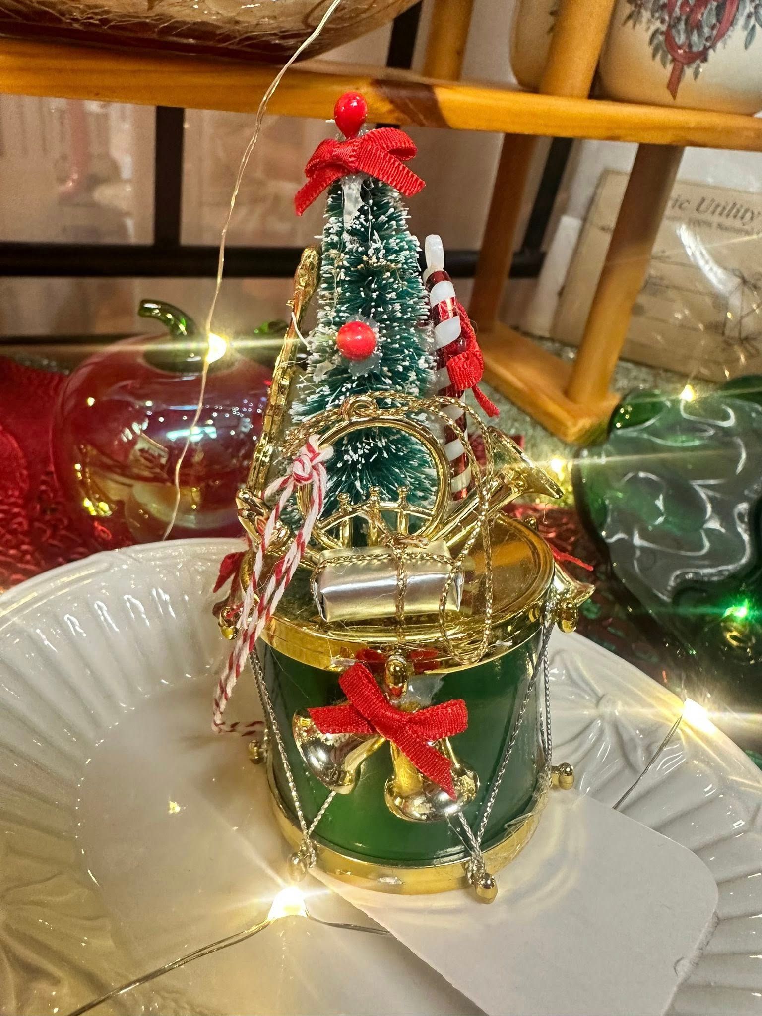 Christmas tree decoration on a white plate. Green and gold with red bows, ornaments and lights.
