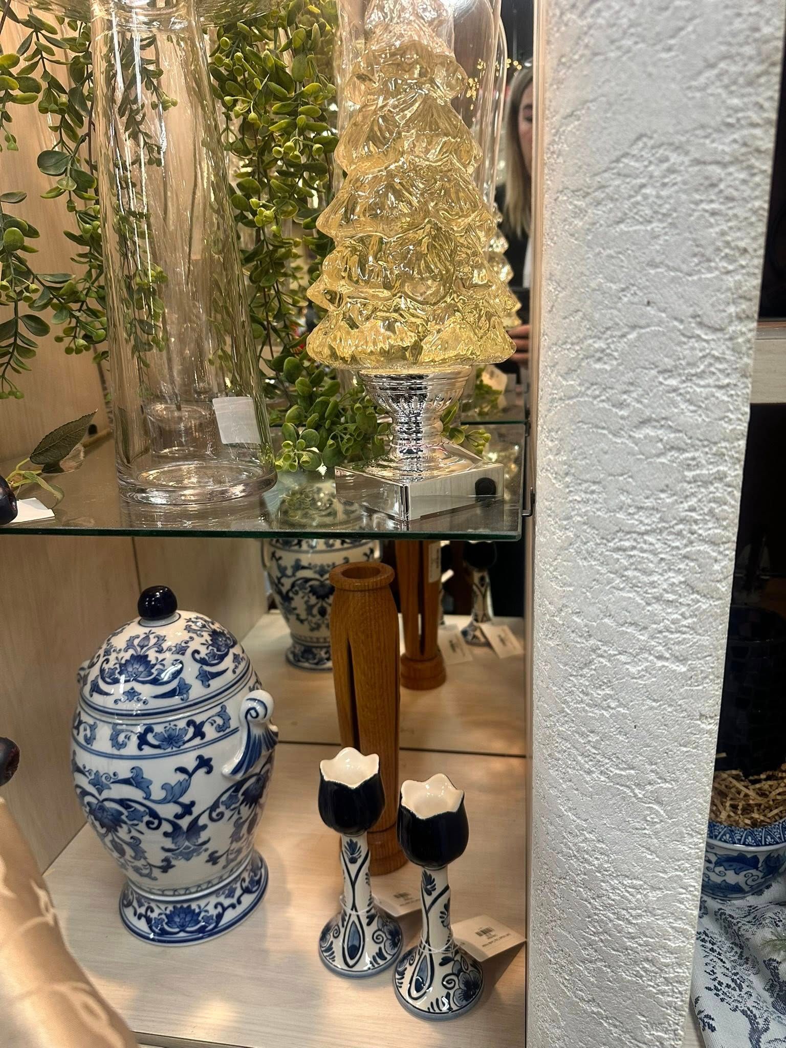 Display case with decorative items: blue and white porcelain, glass vases, and a glowing tree.