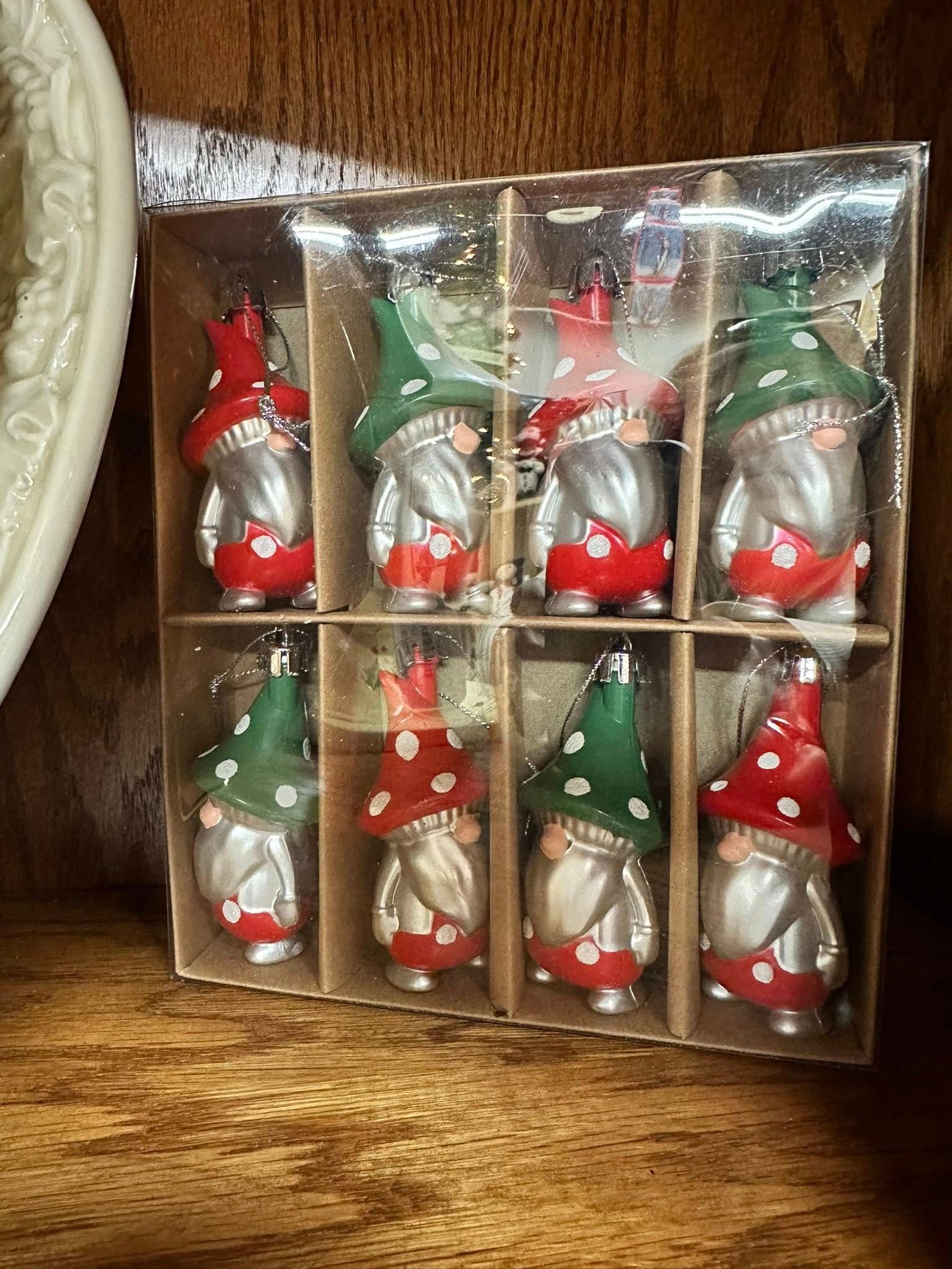 Eight gnome ornaments in a box, alternating red and green polka-dot hats, silver bodies, and red suits.
