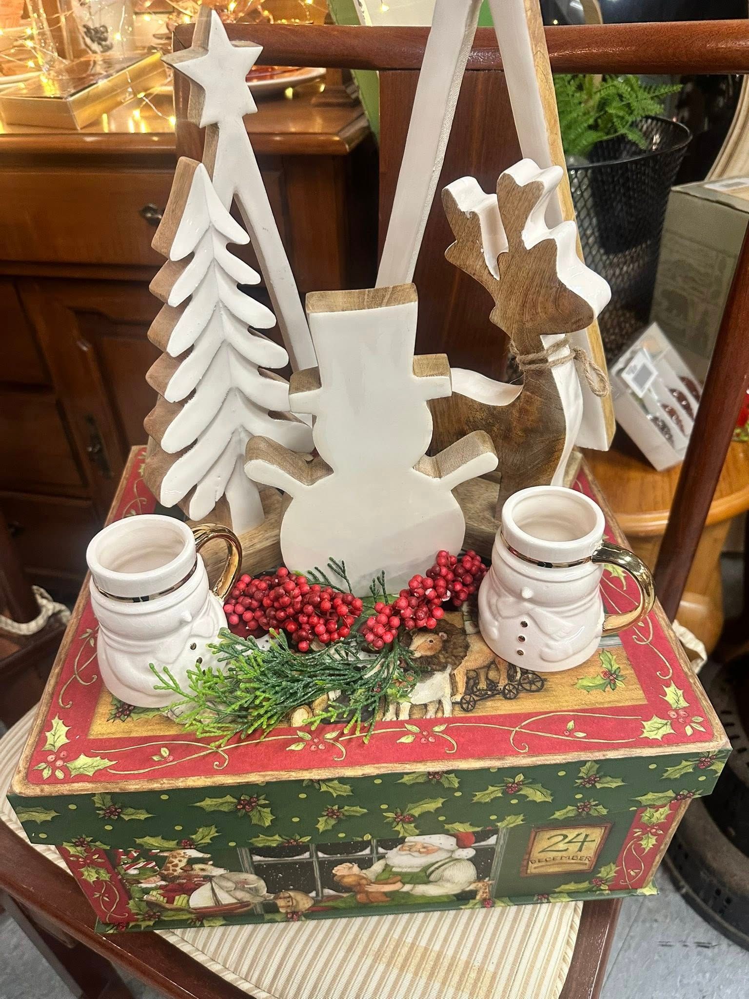 Christmas display with snowman, trees, red berries, and candle holders on decorative box.