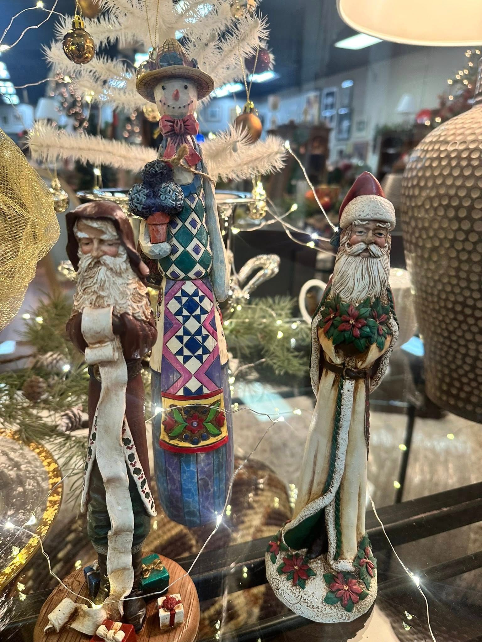 Christmas figurines: Santa holding wreath, Santa with list, and a snowman-like figure on display.