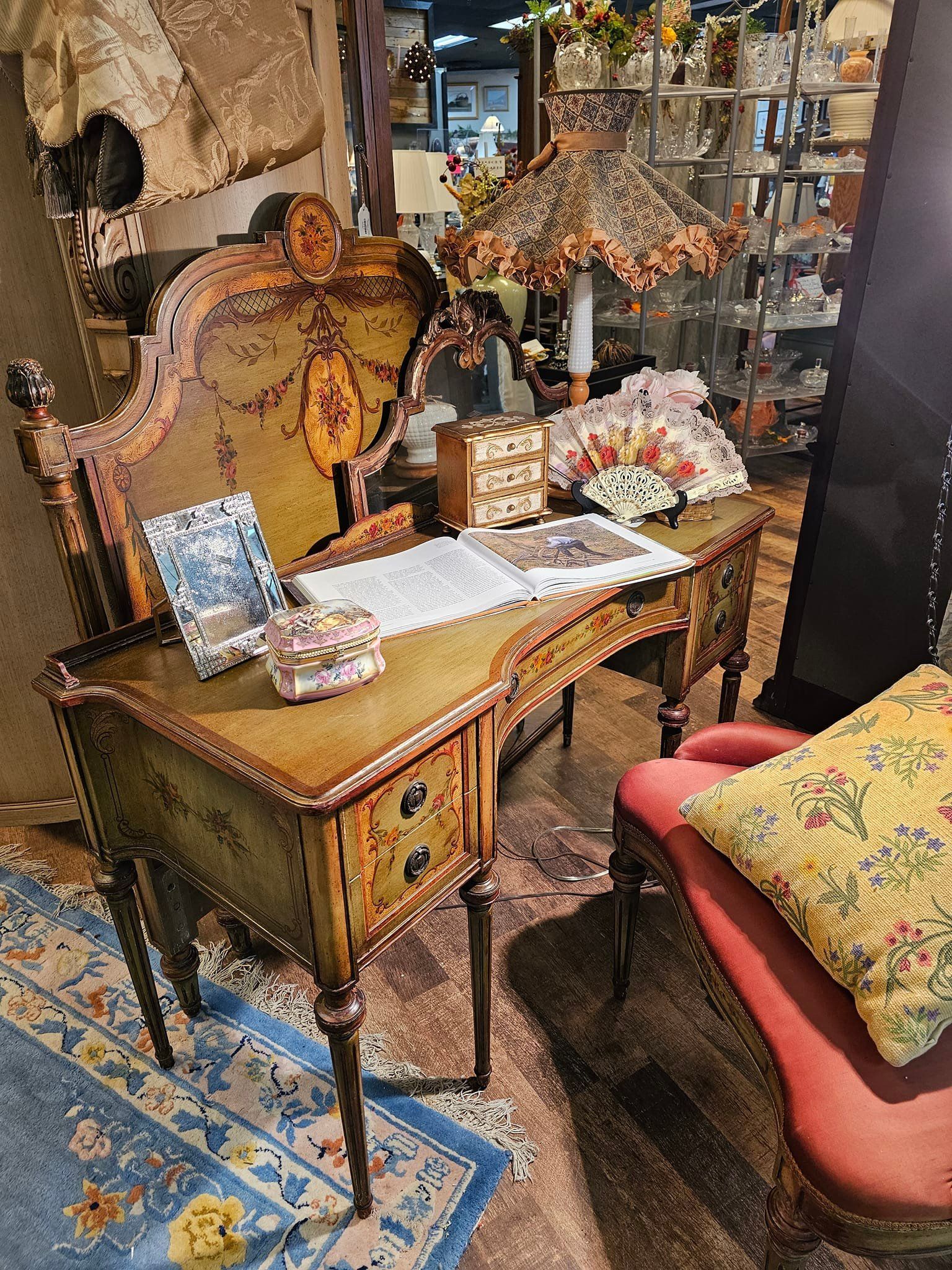 Paintings in ornate frames displayed on a wooden easel. Various landscapes and floral still life scenes.