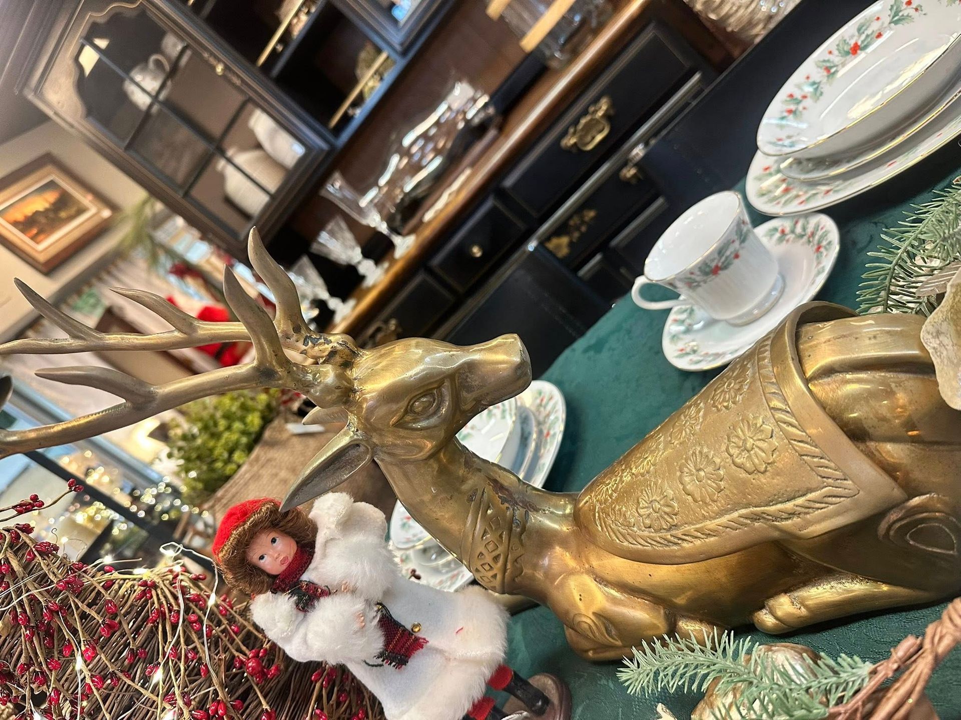 Brass camel and deer figurines with a doll, tea cup, and Christmas decor.