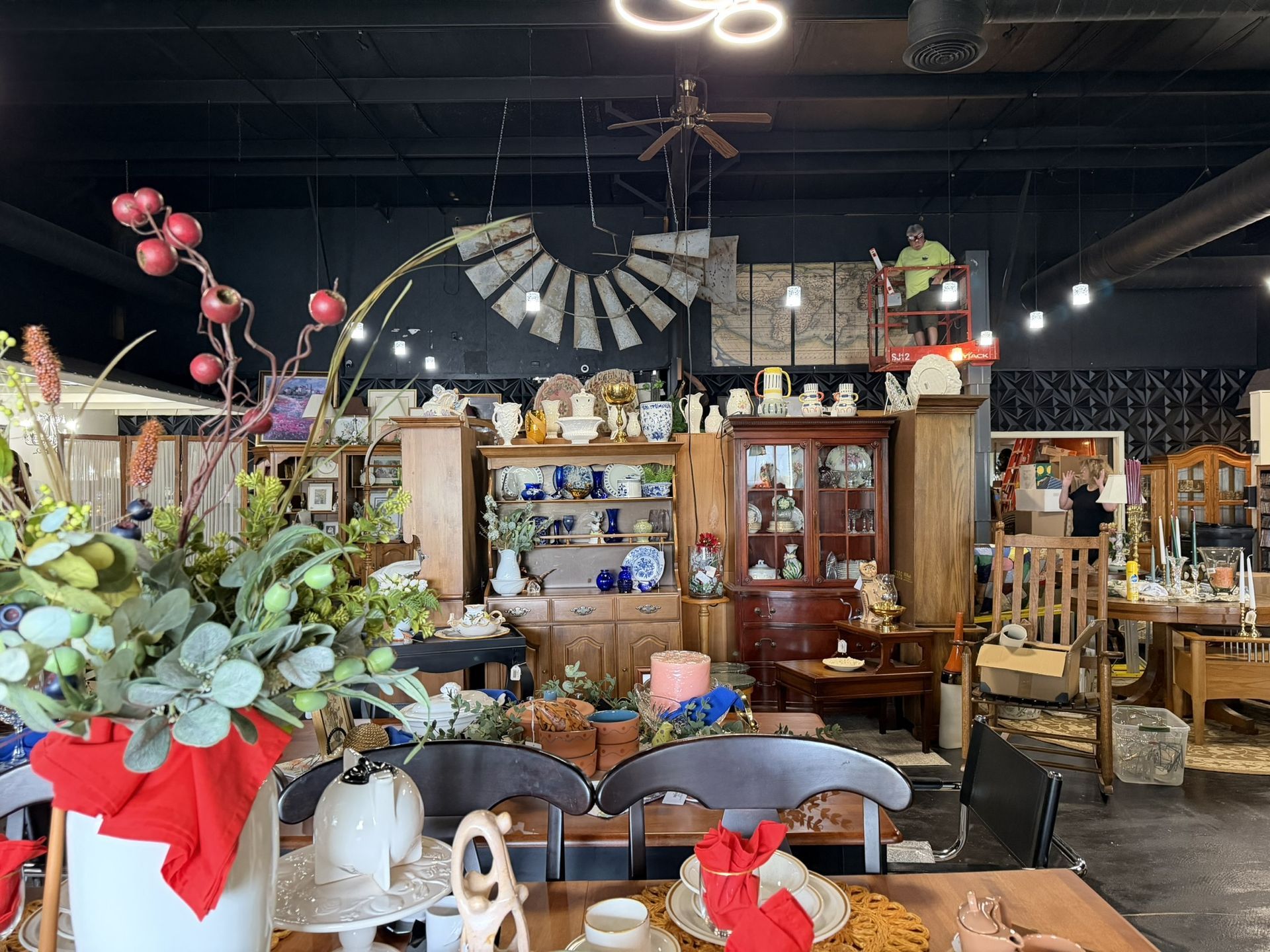 Rustic antique shop interior with shelves of decor, wooden furniture, and floral arrangements