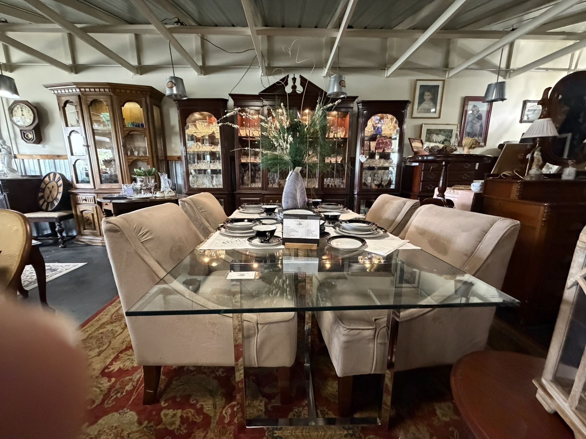 Elegant dining room with glass table, beige chairs, and dark wood cabinets displayed around the room